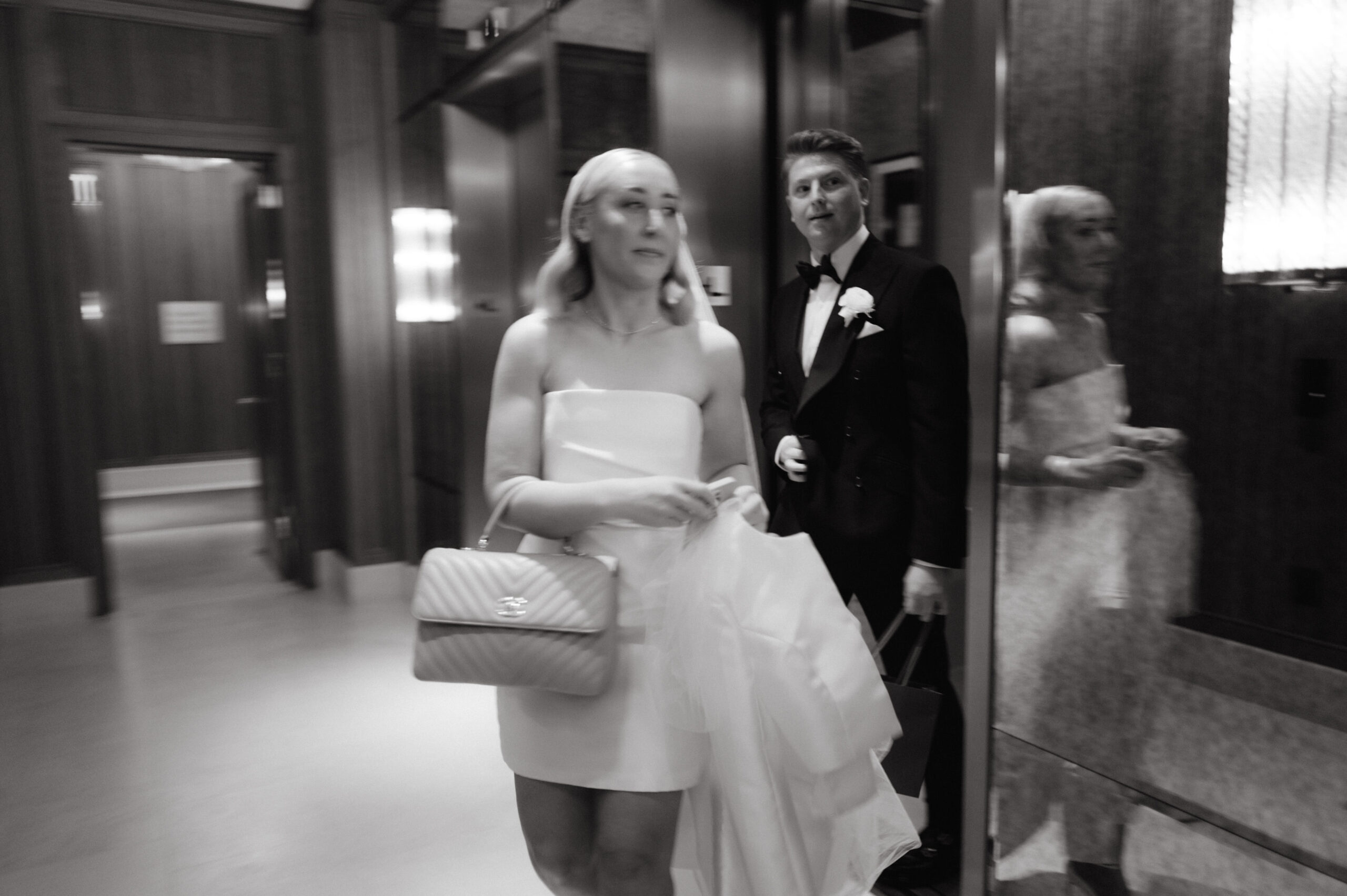 Black and white image of the bride and groom going out of the hotel for the wedding ceremony. Candid wedding photography image by Jenny Fu Studio 
