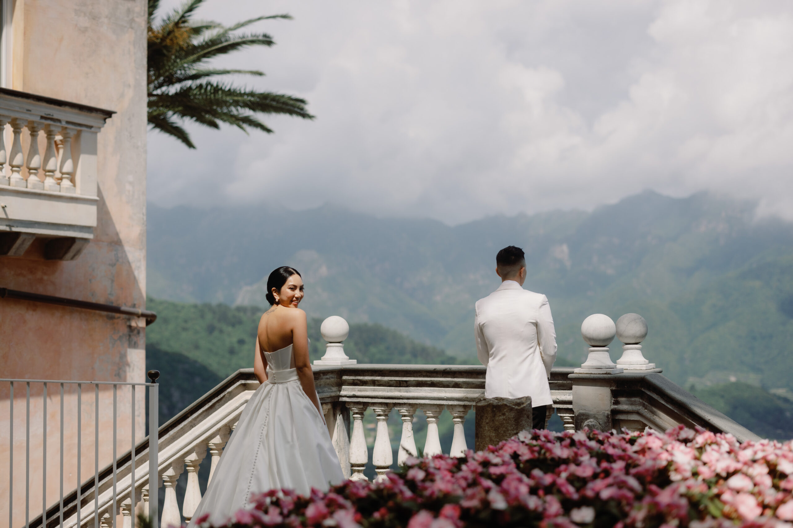 First look image amidst beautiful mountain view, historic villa, and beautiful flowers. Wedding in Italy image by Jenny Fu Studio