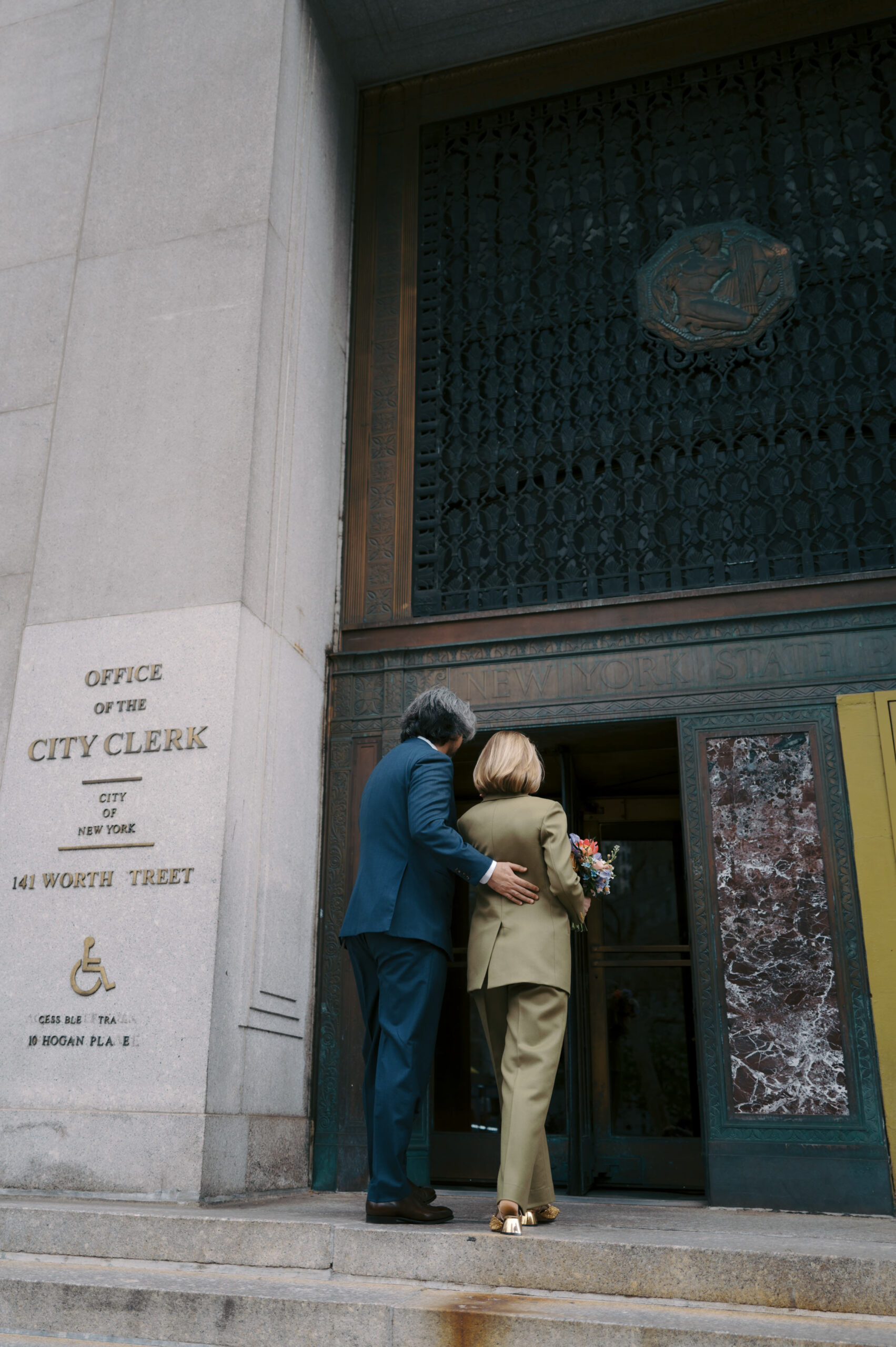 The bride and groom are entering the City Clerk's office in Manhattan. NYC City Hall Elopement image by Jenny Fu Studio