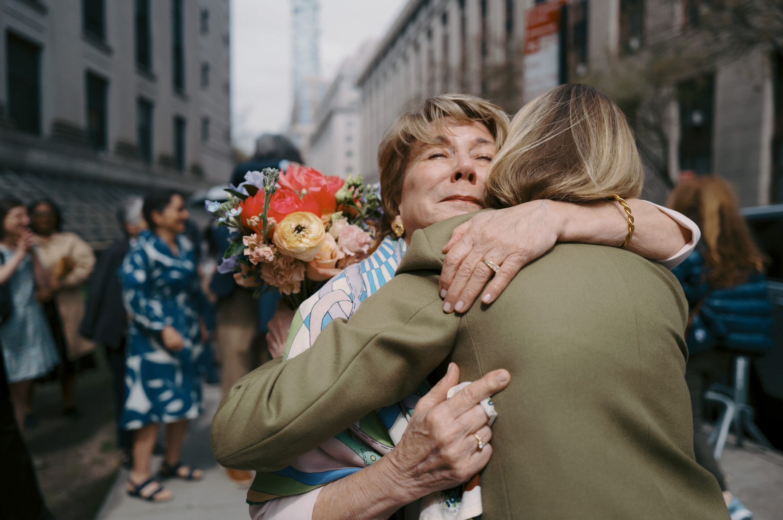 The bride is hugging her mom tightly as she greets her outside NY City Hall after the wedding ceremony. Image by Jenny Fu Studio