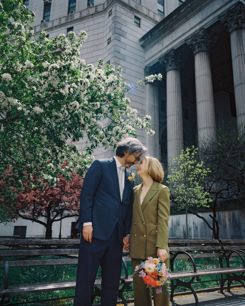 Portrait of the Newlyweds after their Spring NYC City Hall Elopement, with large columns in the background. Image by Jenny Fu Studio