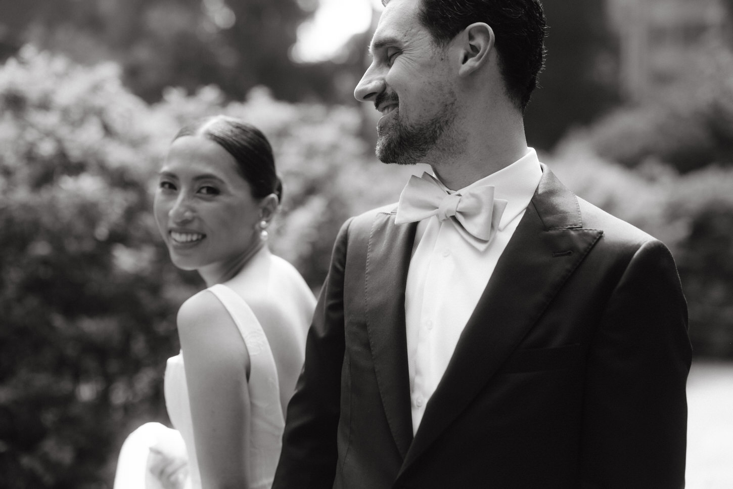 A black and white image of the fashion-forward bride and her groom outdoors, taken by Jenny Fu Studio, NYC.