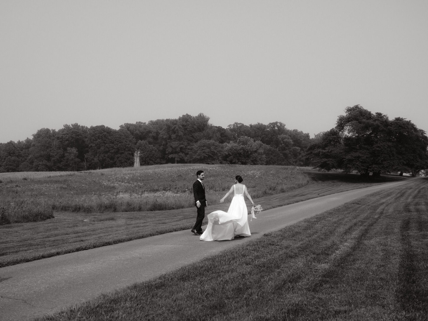 The bride and groom are walking on a beautiful countryside landscape in a cinematic wedding photography by Jenny Fu Studio. 