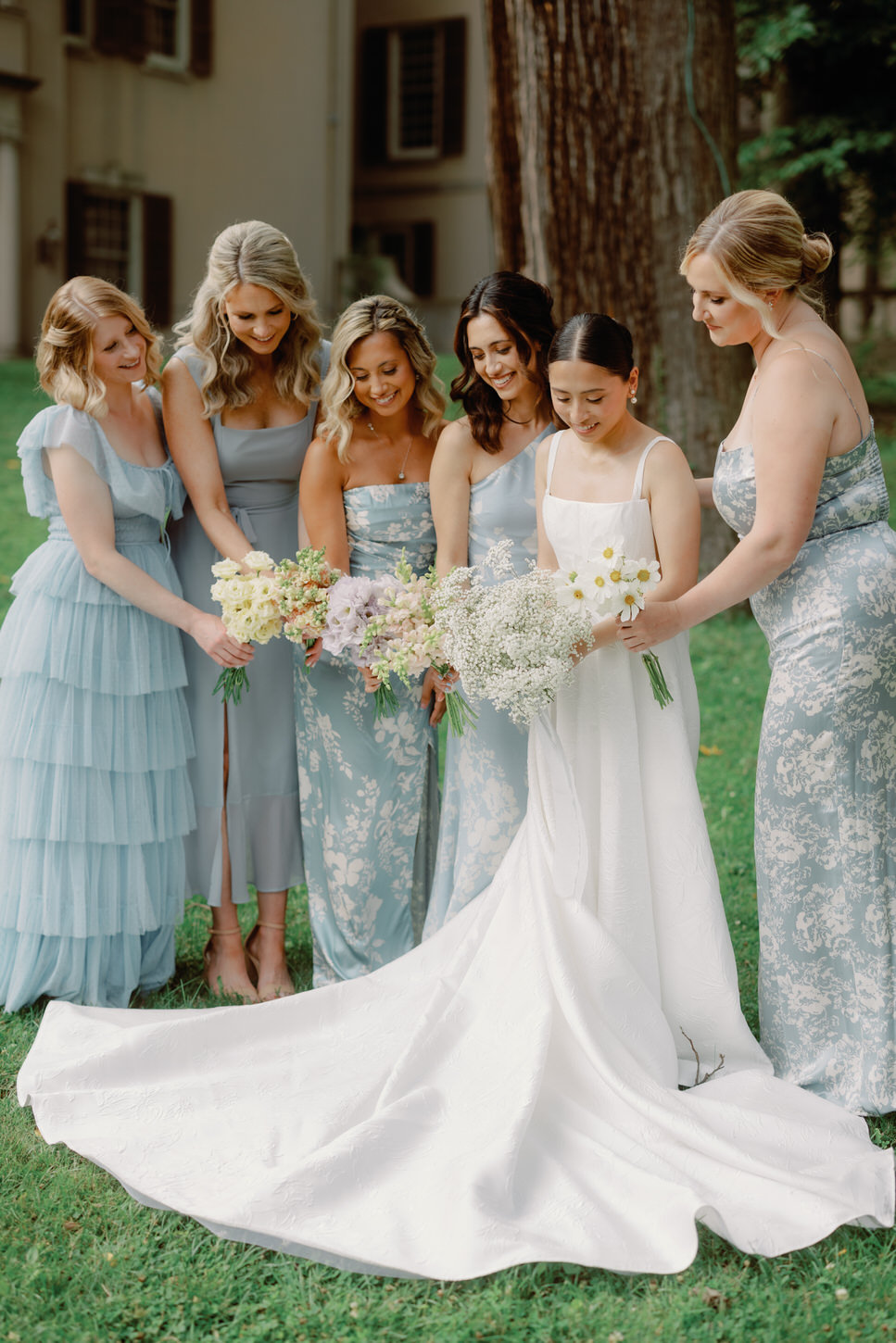 The bride and her bridesmaids are happily holding their beautiful flower bouquets.