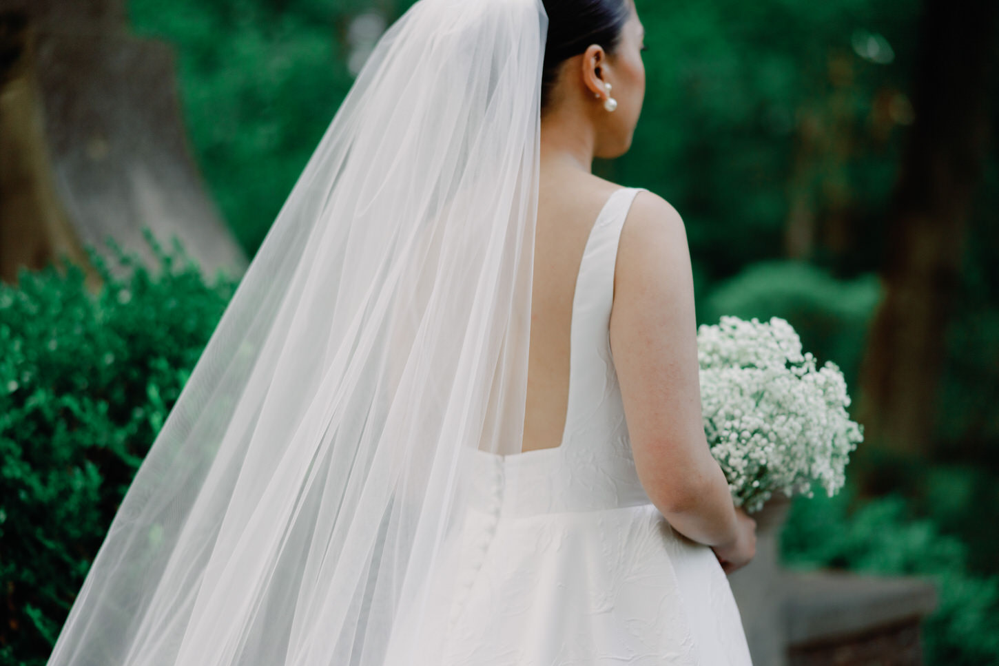 A photojournalistic image of the bride on her back, emphasizing her backless wedding dress and long veil.