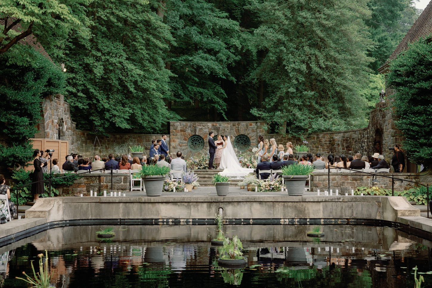 A cinematic wedding photography image of a wedding ceremony with a lush greenery background by Jenny Fu Studio.