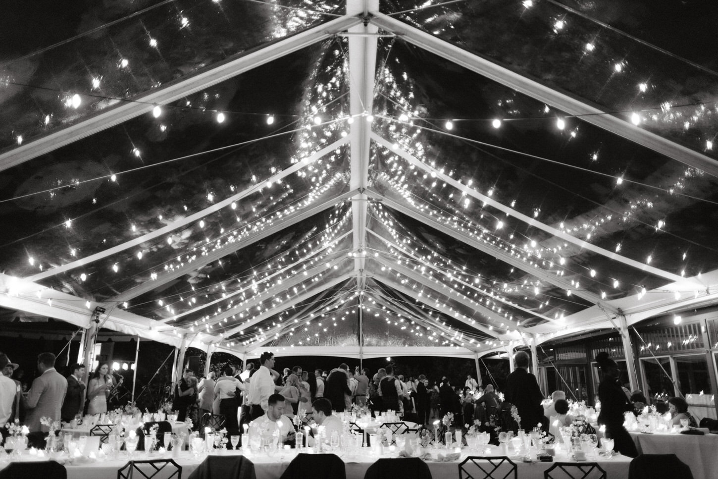 A evening shot of a stunning wedding reception set-up with fairy lights and candle centerpieces by Jenny Fu Studio.