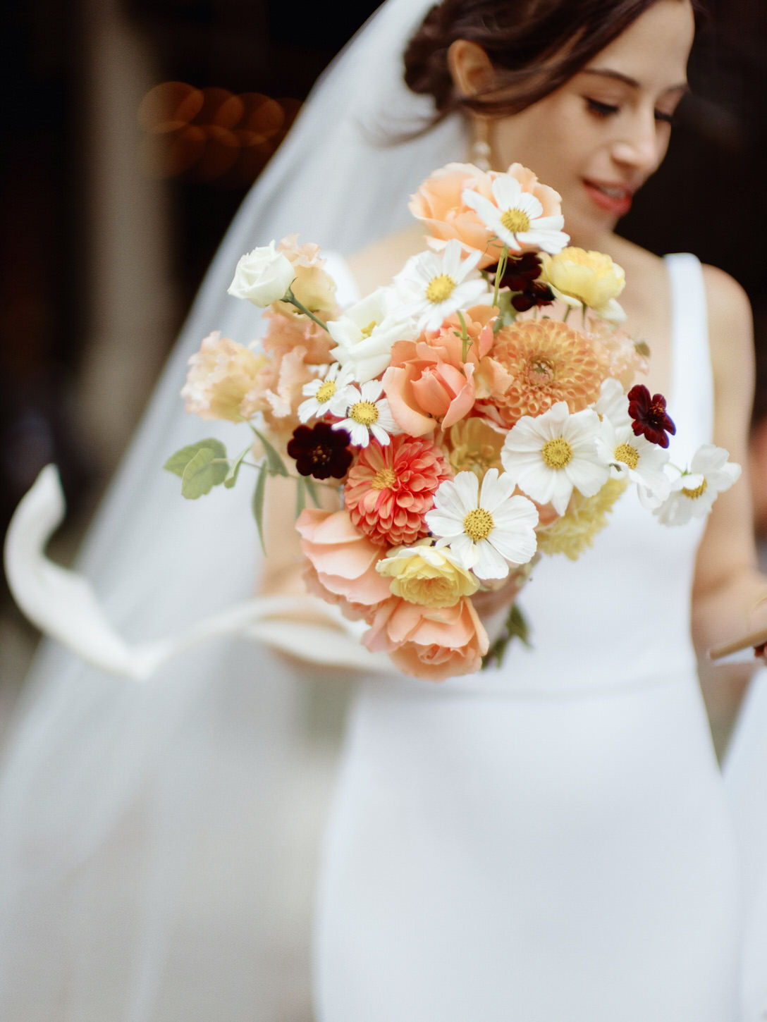 Radiant flower bouquet in shades of peach, yellow and white is held by the bride. Luxurious wedding image by Jenny Fu Studio