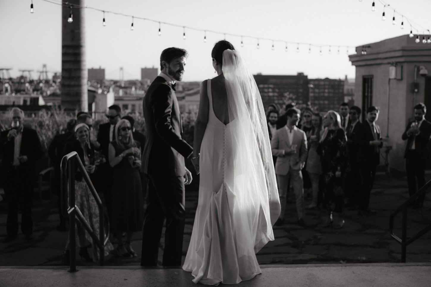 Black and white image of the bride and groom coming out to meet their guests in the cocktail hour. Image by Jenny Fu Studio