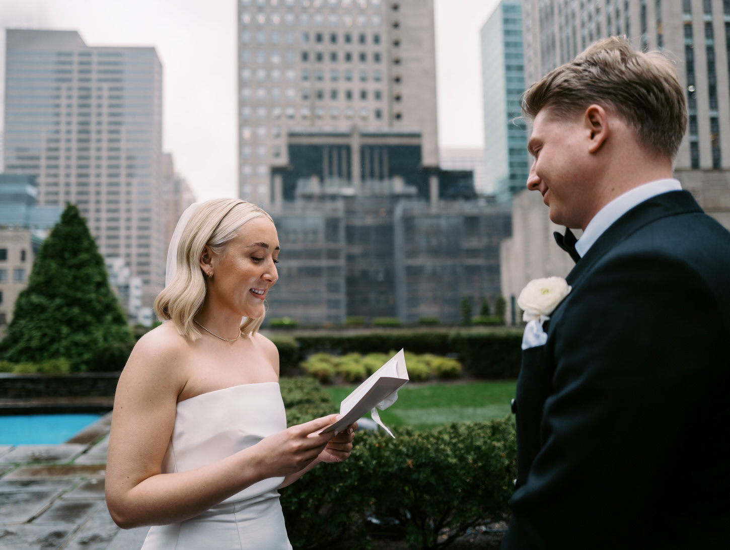 The bride is thoughtfully reading the letter to her groom in 620 Loft and Garden, NYC, while the groom lovingly smiles at her. This candid scene is perfectly captured by Jenny Fu Studio