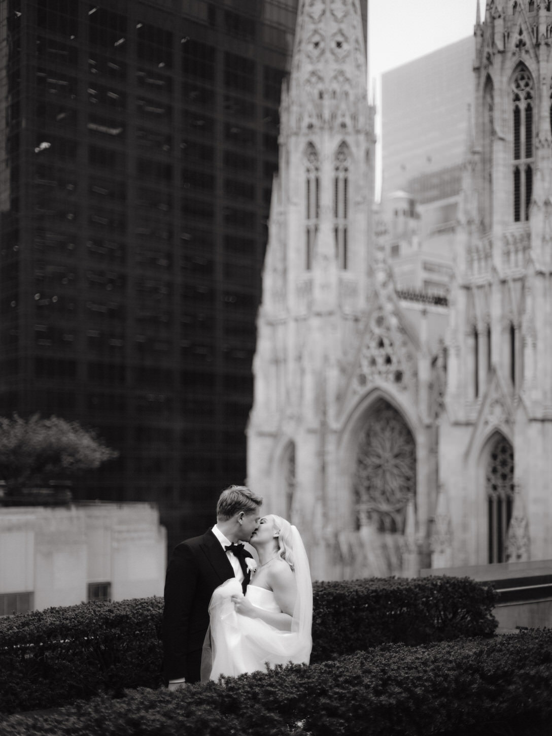 The bride and groom lovingly kisses each other with the Magnificent St. Patrick's Cathedral in NYC in the background, marvelously captured by Jenny Fu Studio.