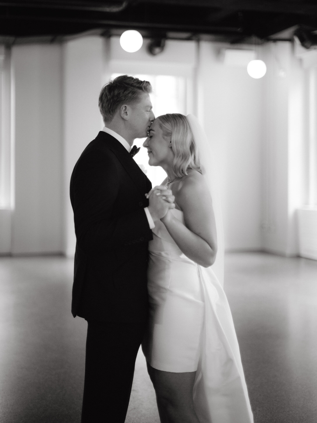 The newlyweds shared a first dance while the groom is tenderly kissing the bride's forehead, under the tented garden area of 620 Loft and Garden.