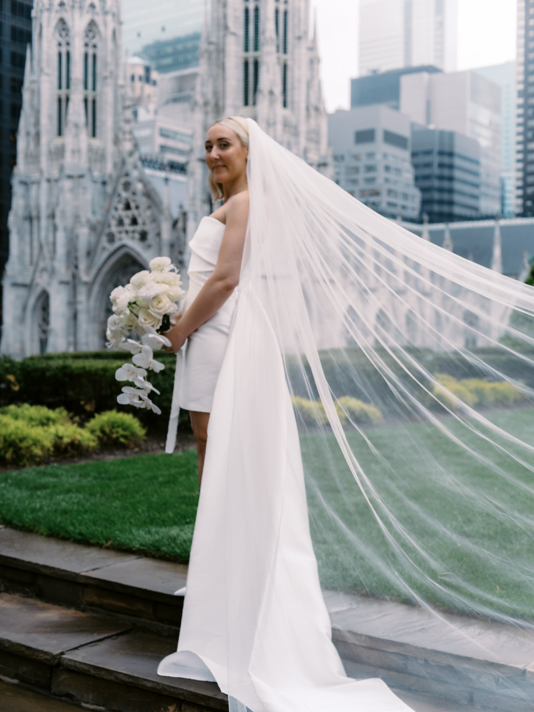 A gorgeous portrait of the bride, holding her flower bouquet, while her veil flows behind her back in her elopement in NYC, captured by Jenny Fu Studio.