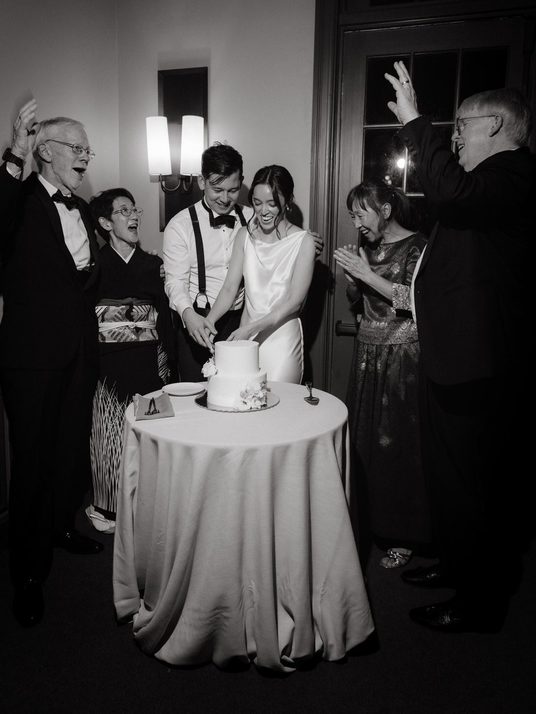 The newlyweds happily cut their cake as their parents cheered on. Image by Jenny Fu Studio