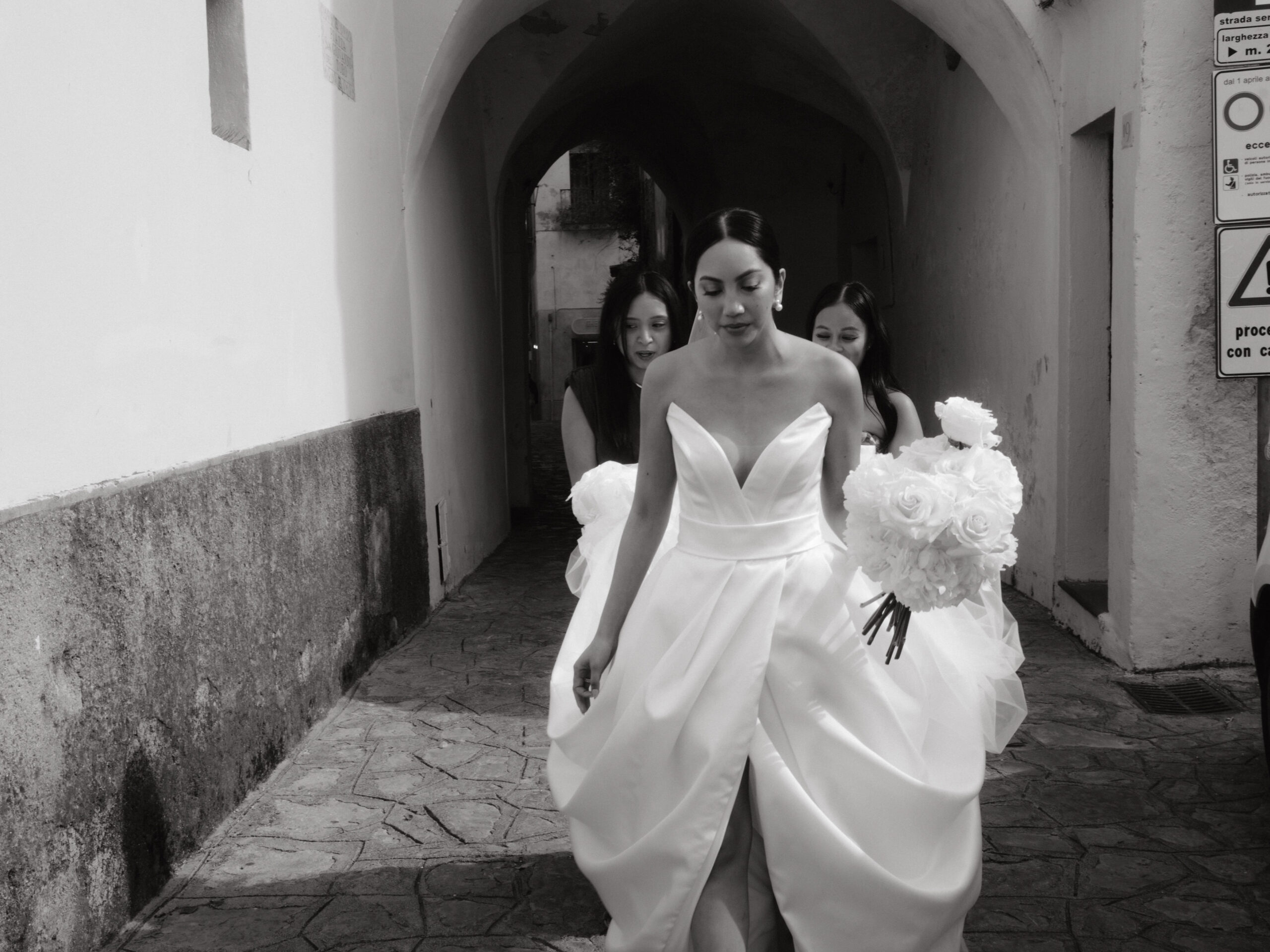 The bride is walking towards the wedding ceremony area with her bridesmaids holding her wedding dress' train, captured by Jenny Fu Studio