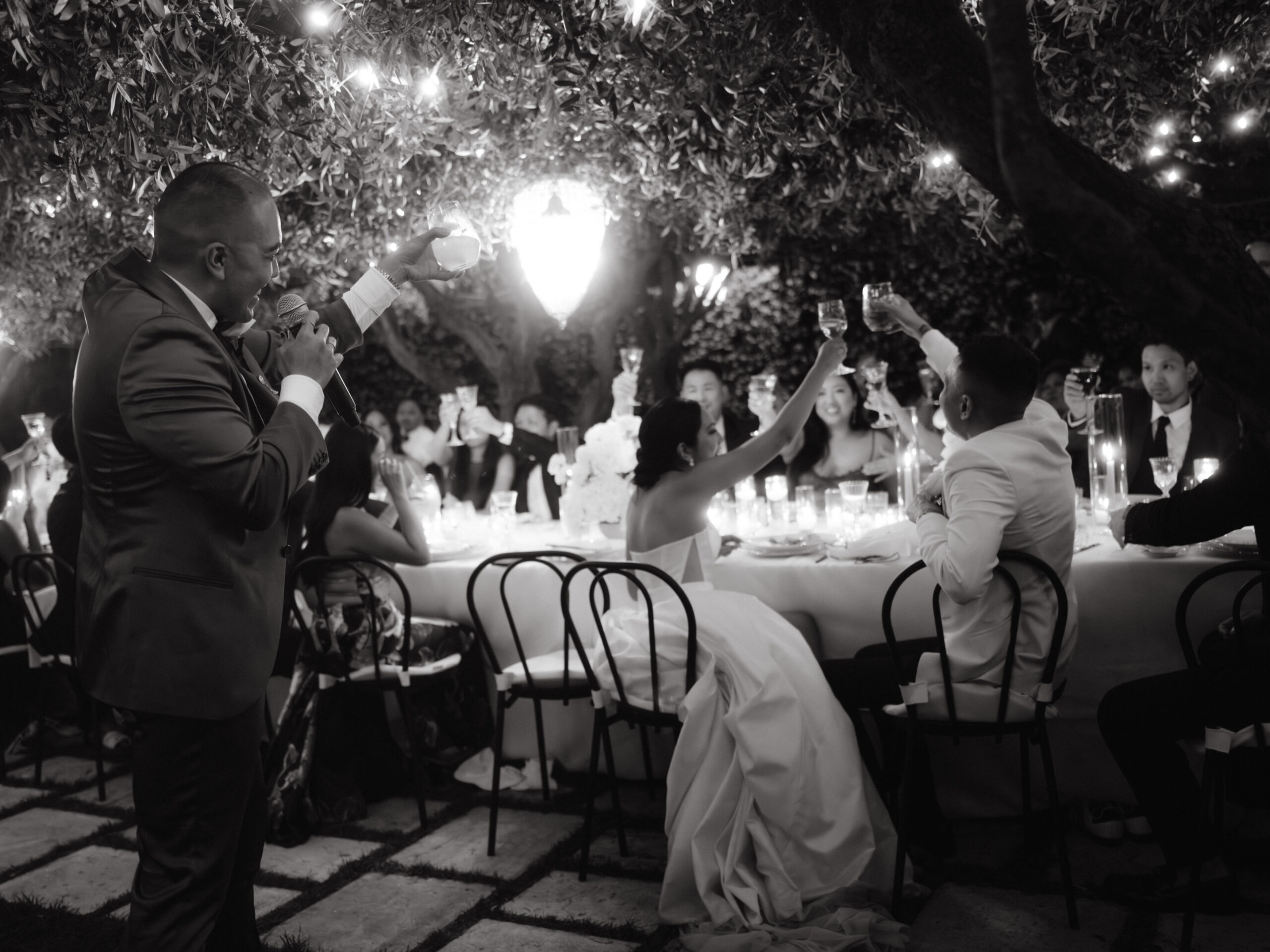 A black and white, photojournalistic image where the newlyweds and the guests share a toast at the reception at Ravello, Italy, captured by Jenny Fu Studio.