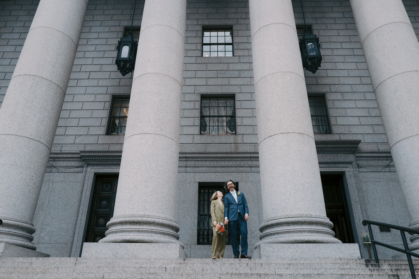 The newlyweds are in front of the iconic NYC City Hall building with beautiful architecture after their spring wedding taken by Jenny Fu Studio.