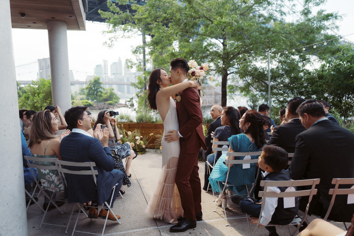 The newlyweds share a kiss in the middle of the wedding aisle after the ceremony, as the guests cheer on, shot by Jenny Fu Studio.