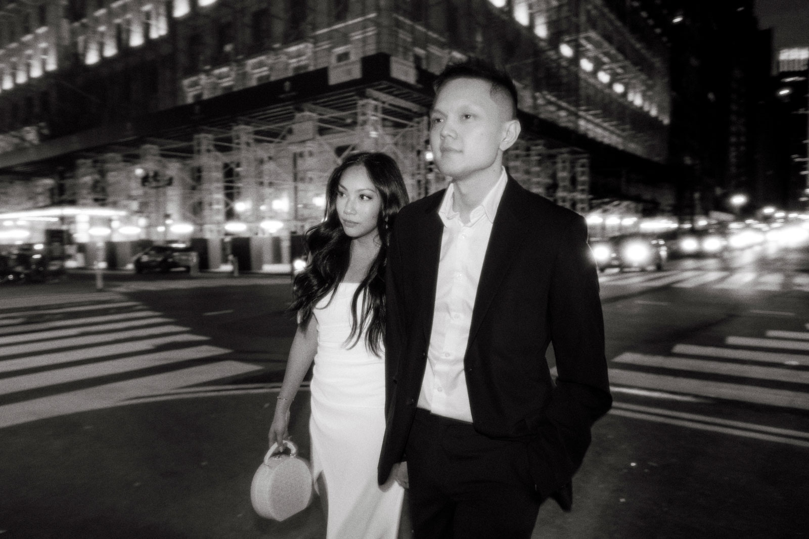 The engaged couple are walking the streets of NYC at night, candidly captured by Jenny Fu Studio using black and white photography.