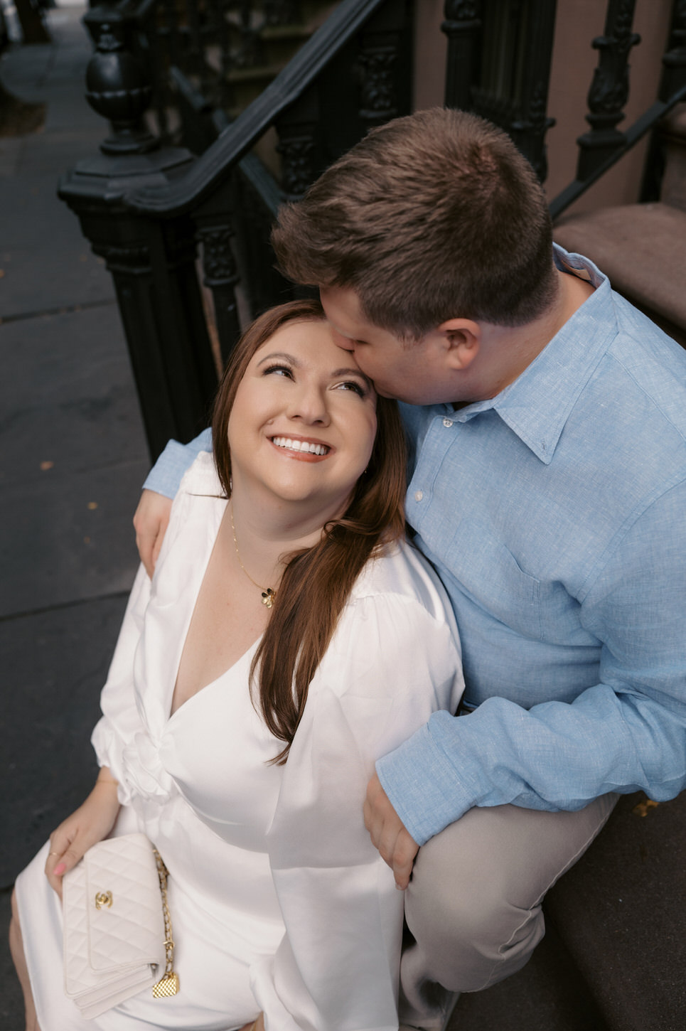 Photojournalistic engagement photo of a man lightly kissing his fiancée on the forehead, captured by Jenny Fu Studio.