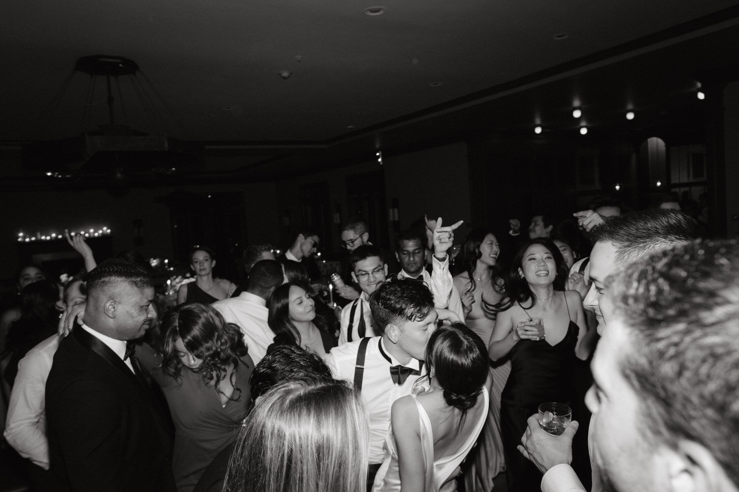 The newlyweds romantically kiss on the dance floor as guests dance to the beat, in a Black-tie wedding captured by Jenny Fu Studio. 