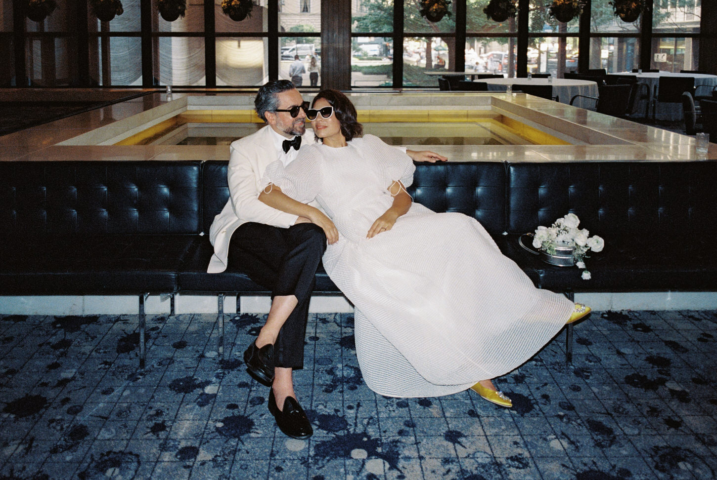 The cool and chic newlyweds are wearing sunglasses while sitting inside a hotel at Roosevelt Island, NYC, captured by Jenny Fu Studio. 