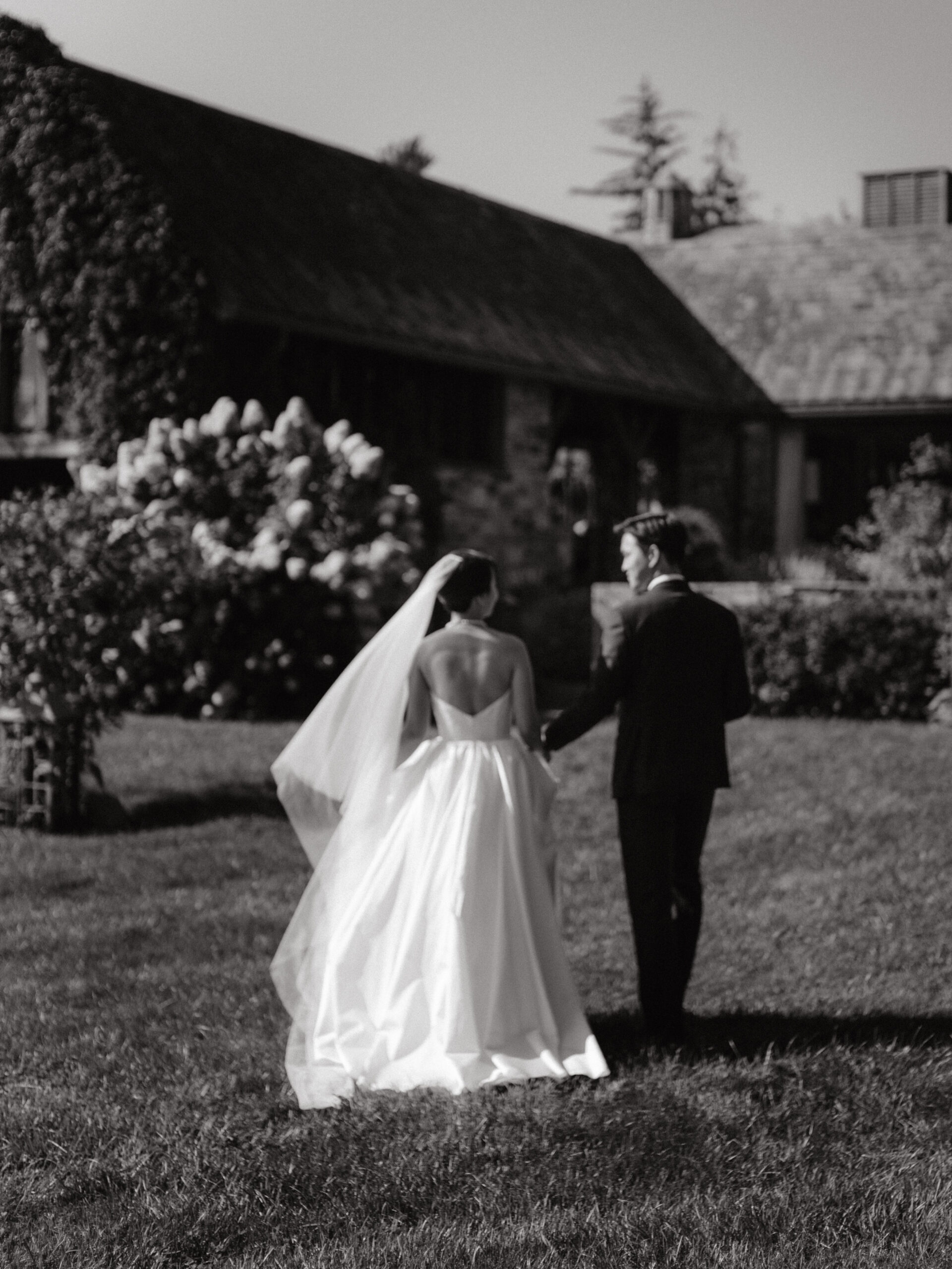 The bride and groom are walking intimately as the bride's veil is gently blown by the wind, perfectly captured by Jenny Fu Studio.