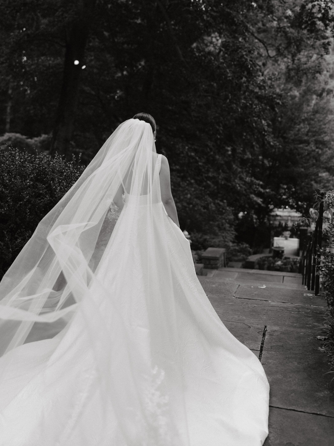 Black and white, editorial image of the bride on her back, with her veil flowing in the air, captured by Jenny Fu Studio.