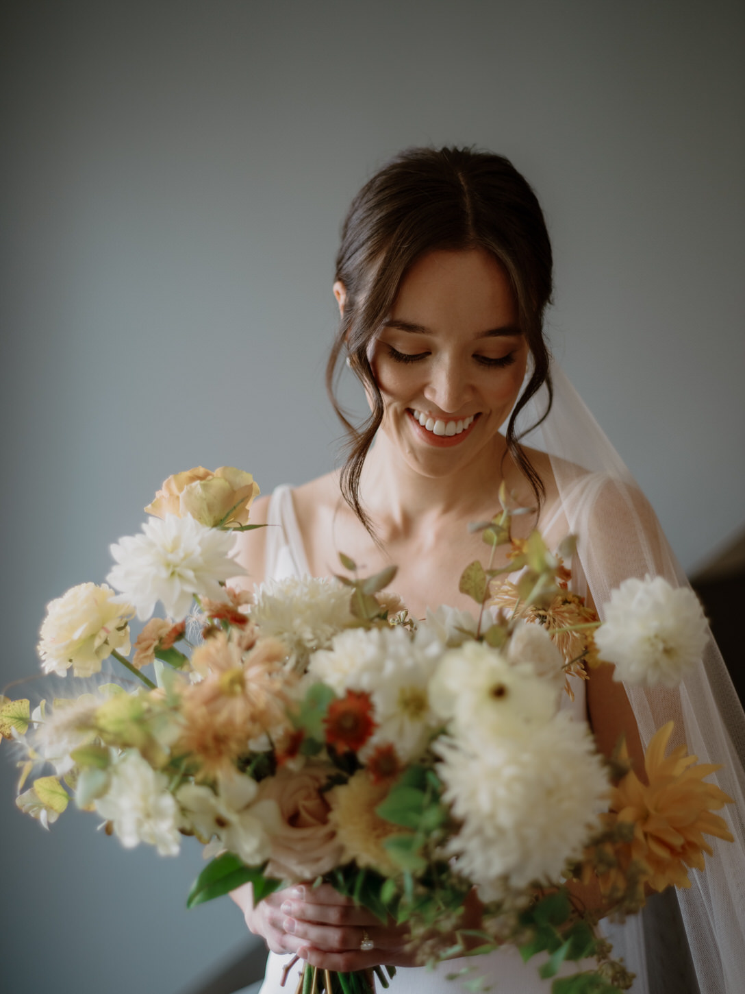 The stunning bride is holding her flower bouquet in fall color palette of forest greens, olives, dark reds, and deep yellows, captured by Jenny Fu Studio.