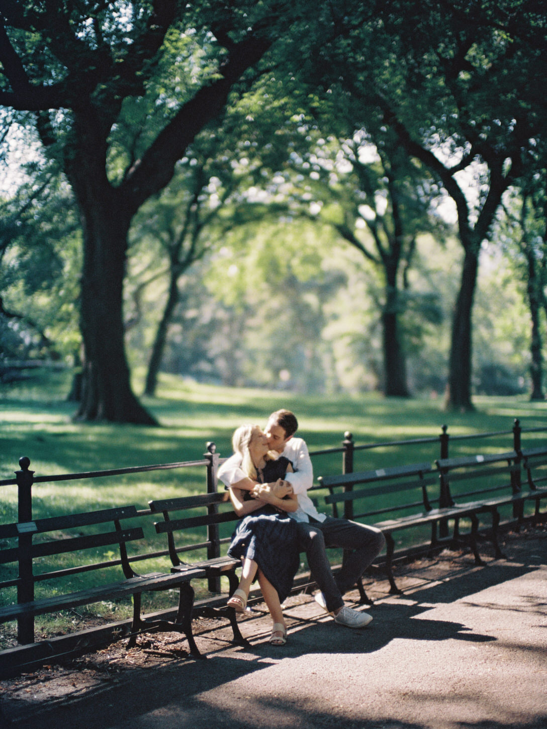 The engaged couple is having a sweet, romantic moment while sitting on a bench at Central Park, New York City, captured by Jenny Fu Studio.