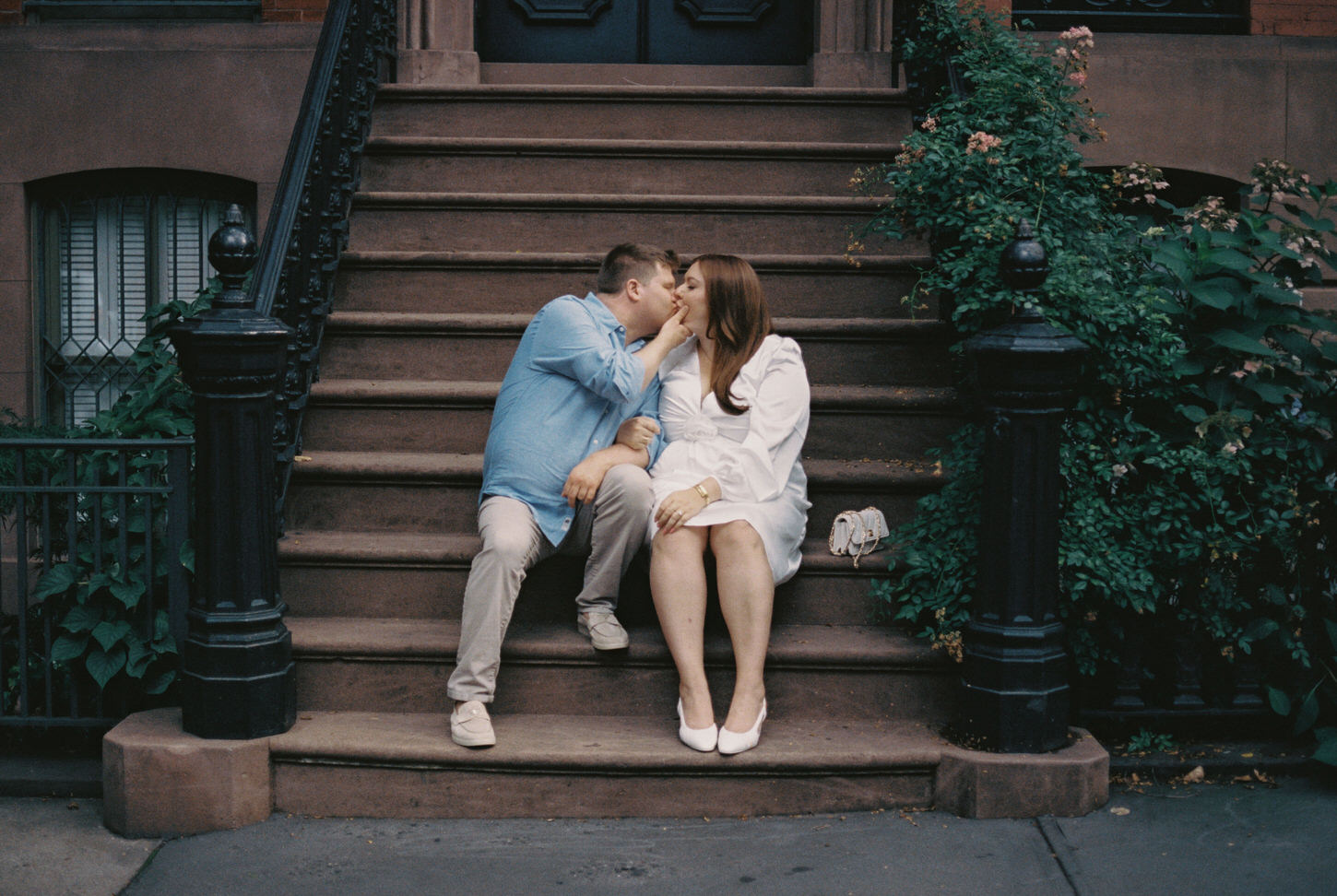 The engaged couple is sitting on a staircase in a house at West Village, NYC, while gently kissing each other captured by Jenny Fu Studio.