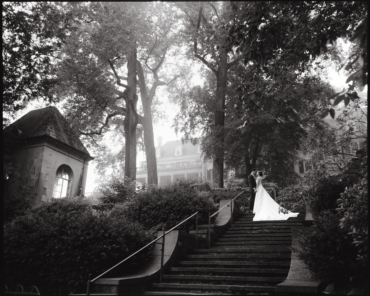 The bride and groom are intimately standing close to each other amongst the large trees and iconic architecture, captured by by Jenny Fu Studio