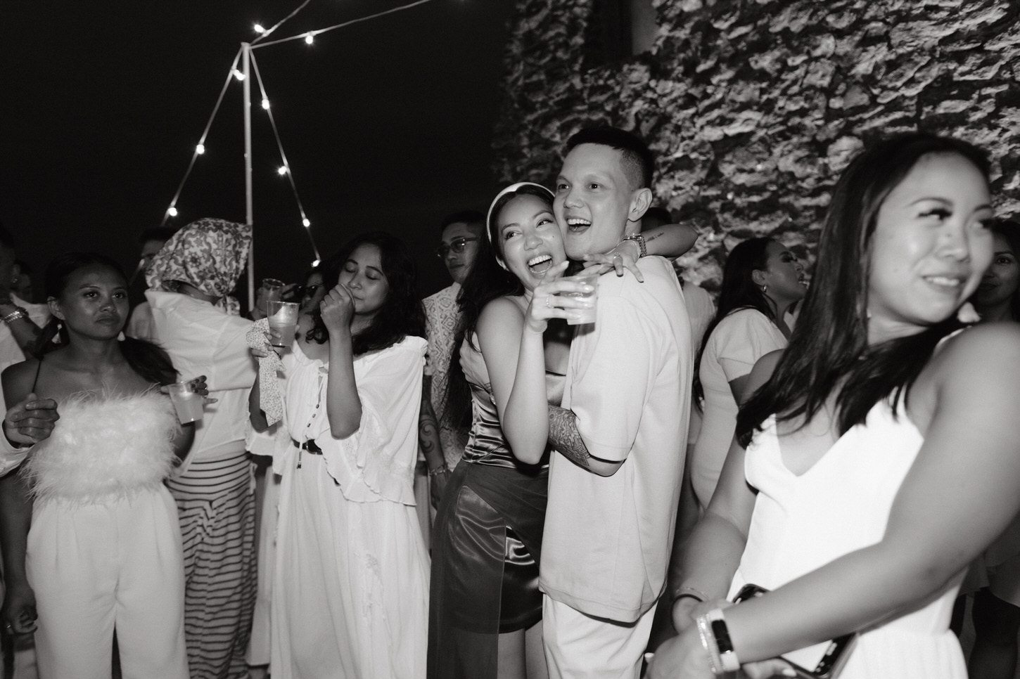 Black and white image of the would-be bride and groom with guests dancing through the night, captured by Jenny Fu Studio for a pre-wedding event.