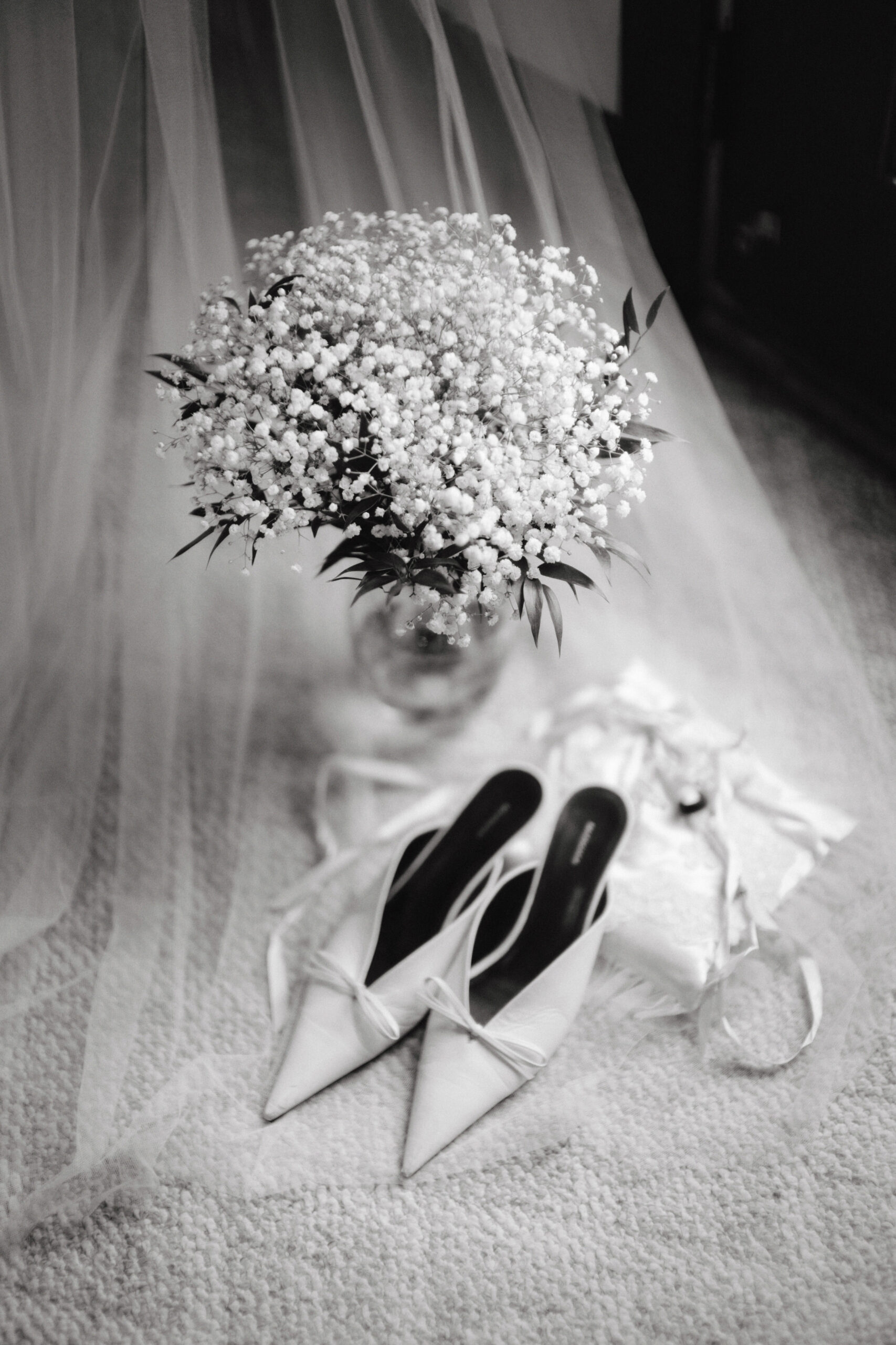 A black and white portrait of the bride's shoes, wedding bouquet and purse captured by Jenny Fu Studio for a luxury wedding album.