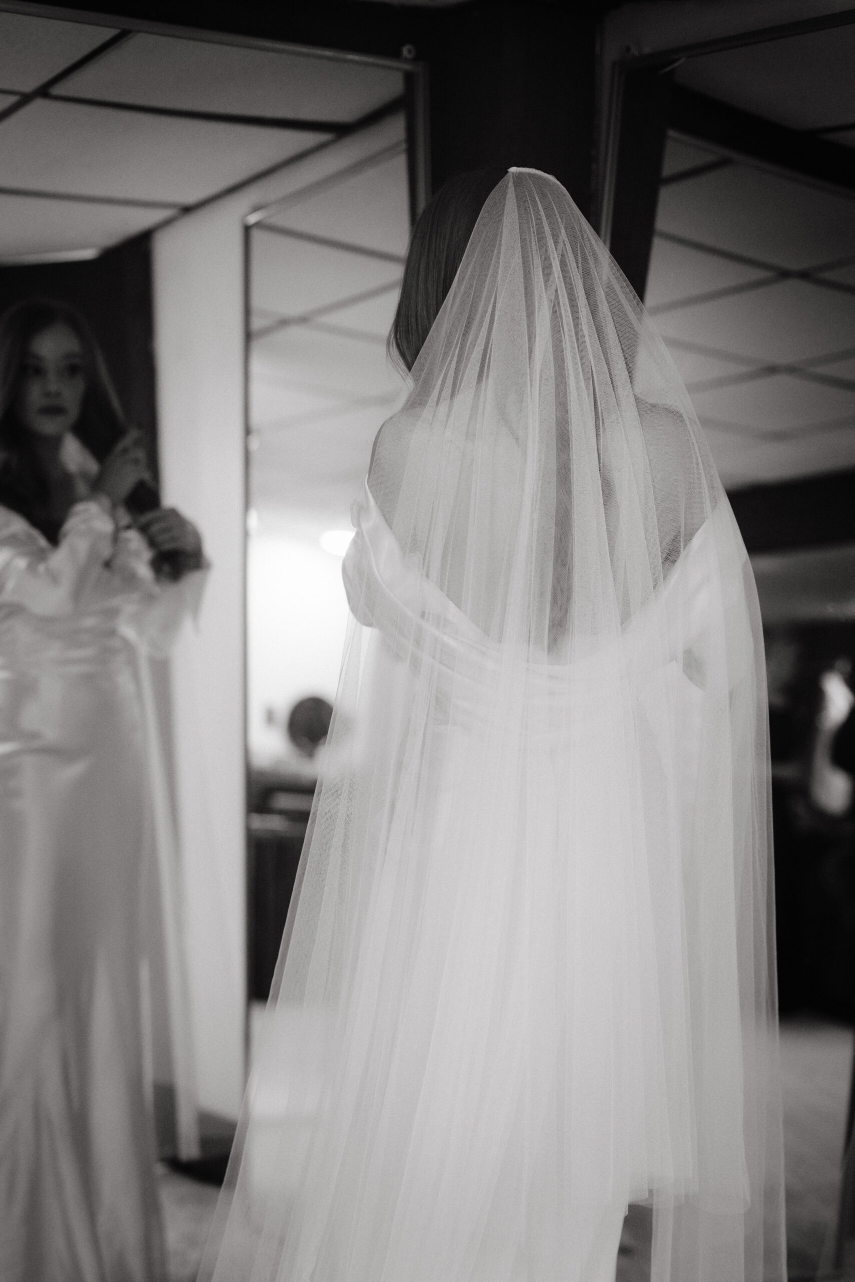 The bride is looking at the mirror, getting ready for her wedding captured by Jenny Fu Studio for a luxury wedding album.