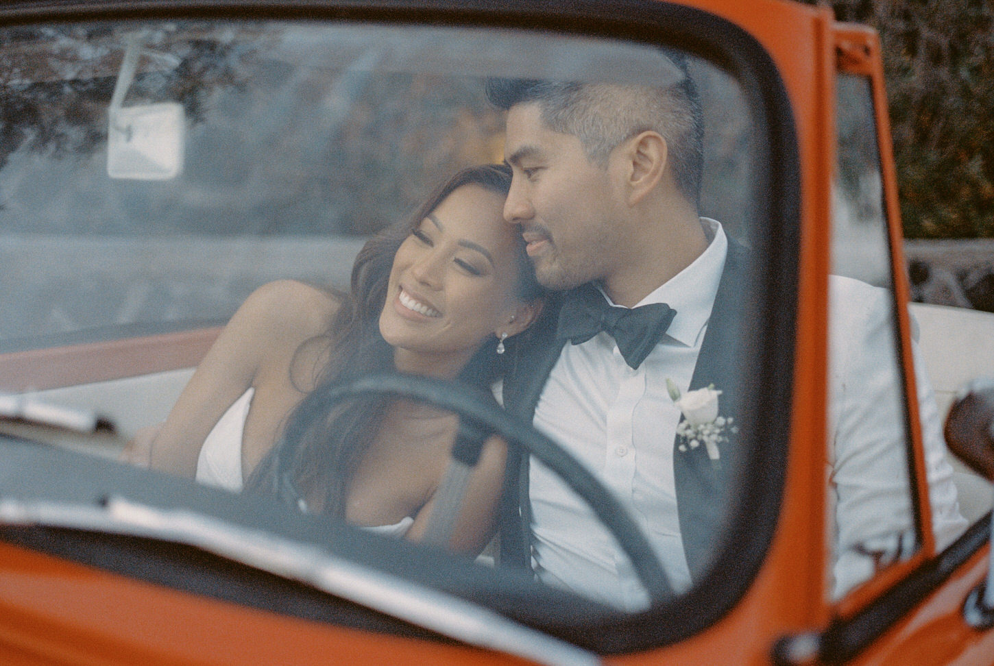 The newly-weds are sharing an intimate moment inside a red vintage car, captured by Jenny Fu Studio.