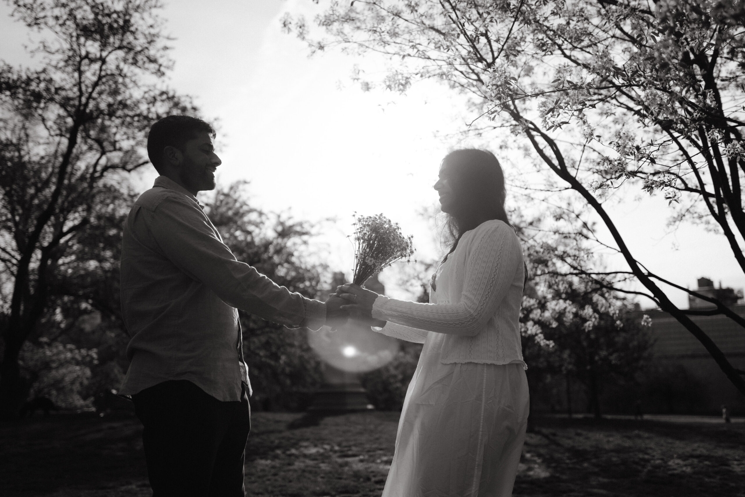 A black and white image of the engaged couple having an intimate moment in a park, captured by Jenny Fu Studio.