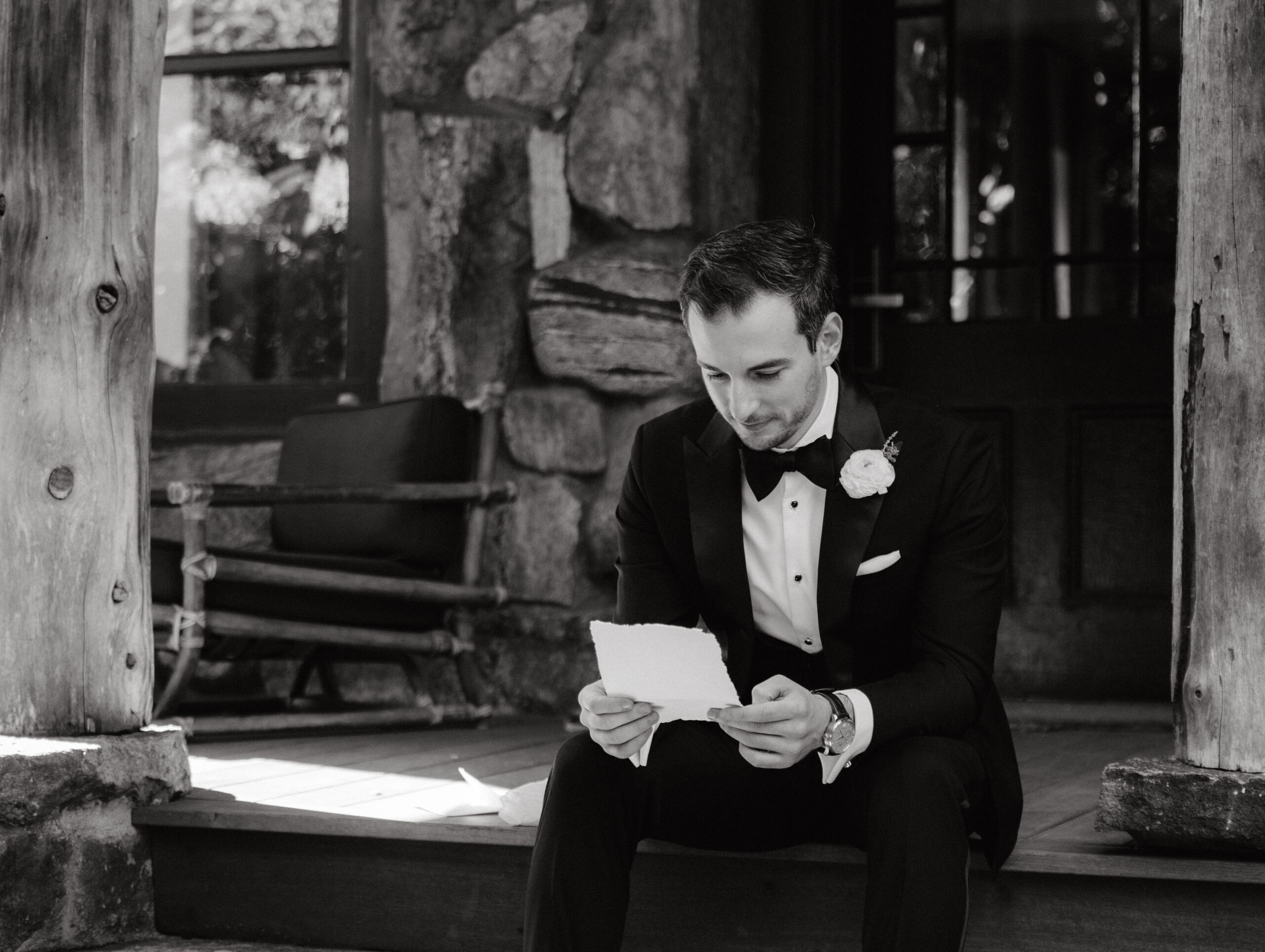 Black and white image of the groom reading the bride's letter before the ceremony, captured in hybrid wedding photography by Jenny Fu Studio