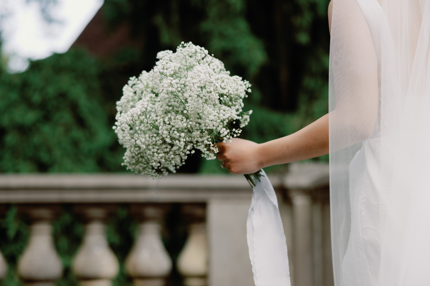 The bride is holding her simple white bouquet as she gaze outdoors, captured in an elegant wedding portrait by Jenny Fu Studio.