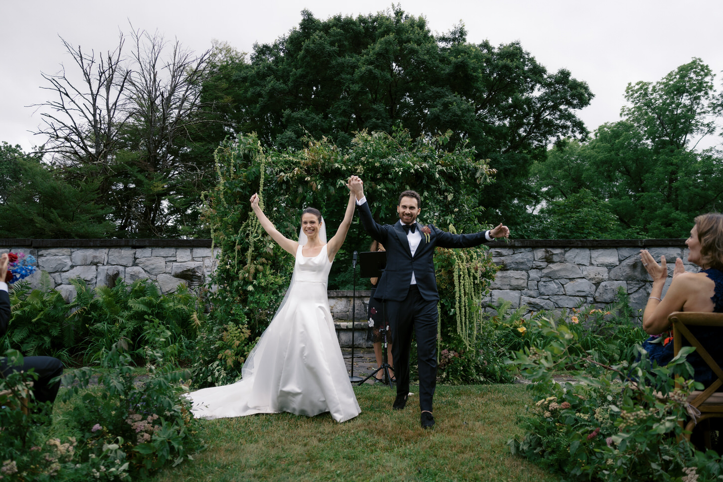 The newlyweds happily walk back in the aisle after the wedding ceremony, as guests cheers on, captured by Jenny Fu Studio.
