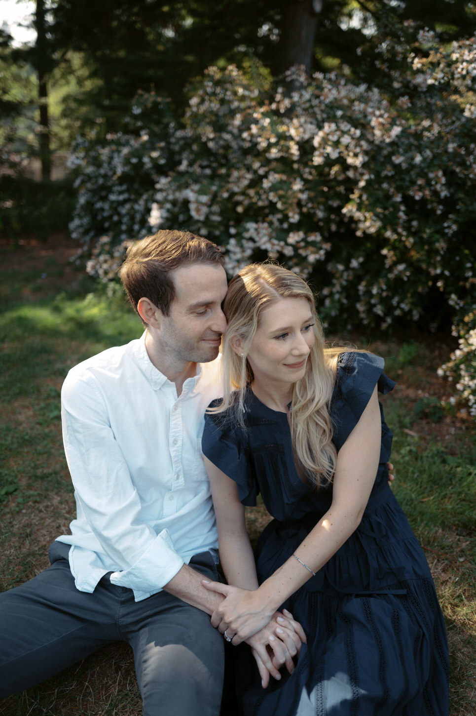 The would-be bride and groom are enjoying a sweet moment in the park, seated on the ground, captured by Jenny Fu Studio.