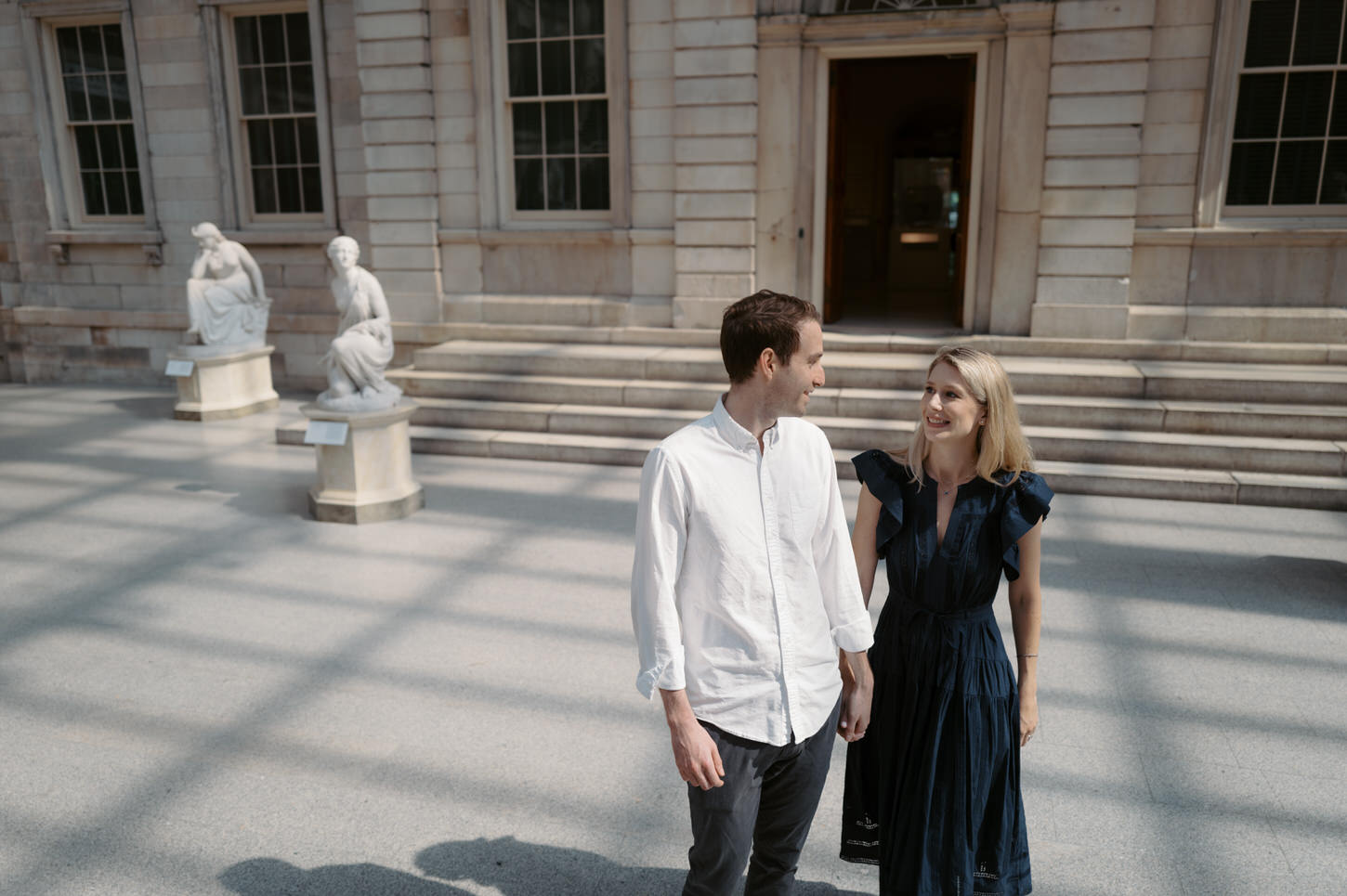 The engaged couple are happily staring at each other's eyes outside The MET Museum, in artistic engagement photo captured by Jenny Fu Studio.