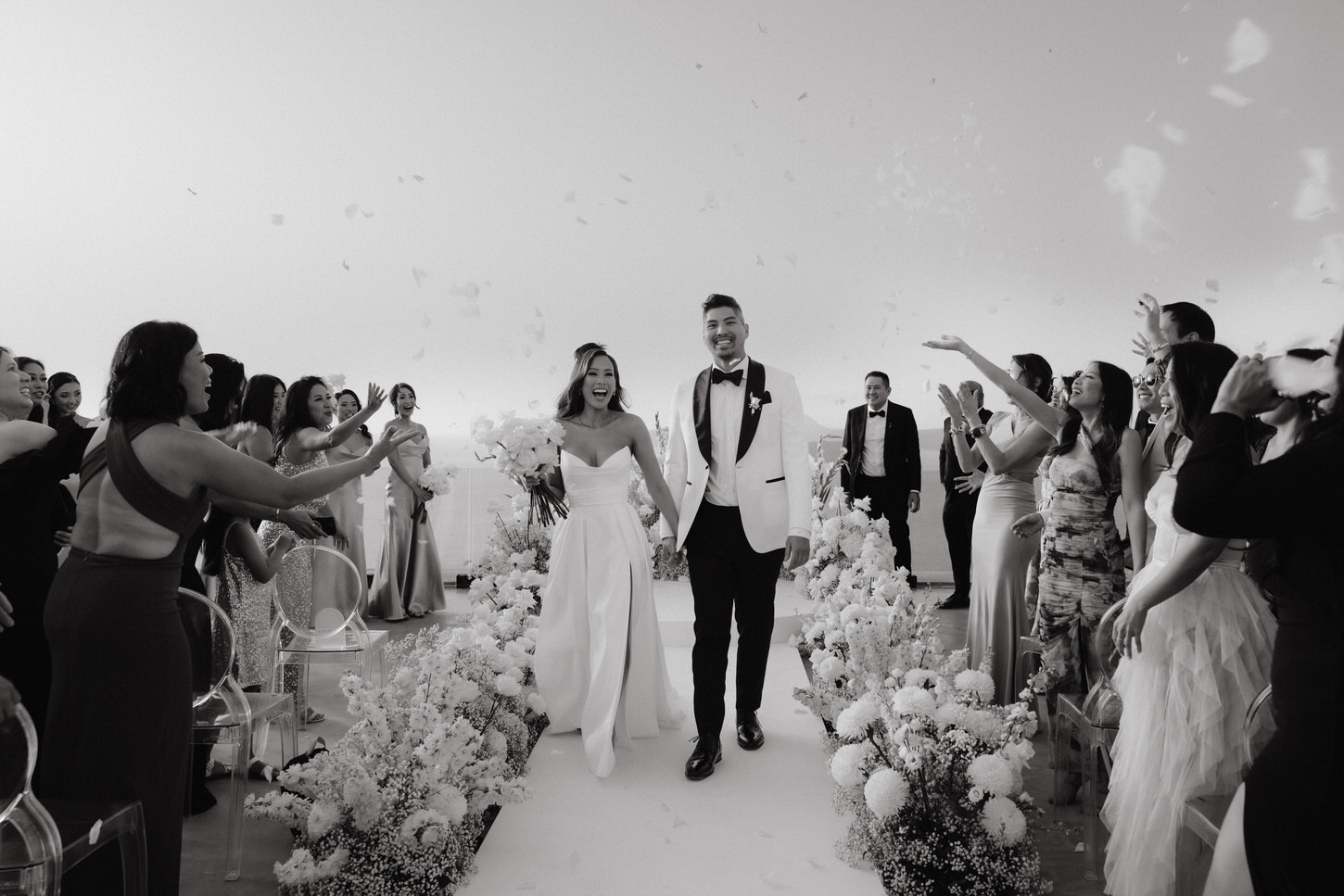 Black and white image of the newlyweds walking back down the aisle after the wedding ceremony in Greece, captured by Jenny Fu Studio.