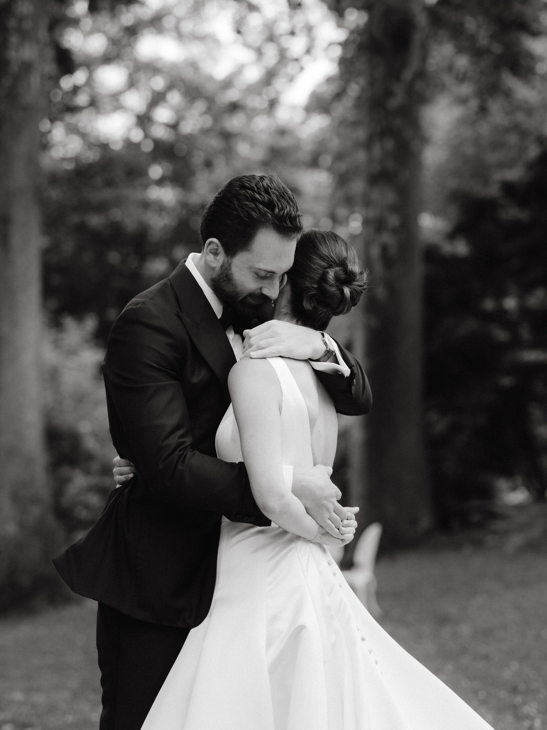 Black and white, candid, first look photo where the groom is emotionally hugging the bride, captured by Jenny Fu Studio.