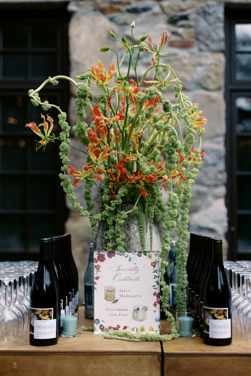 Specialty wedding cocktails lay on a table with a pretty flower centerpiece at an upstate New York wedding, captured by high-fashion wedding photographer Jenny Fu, of Jenny Fu Studio.