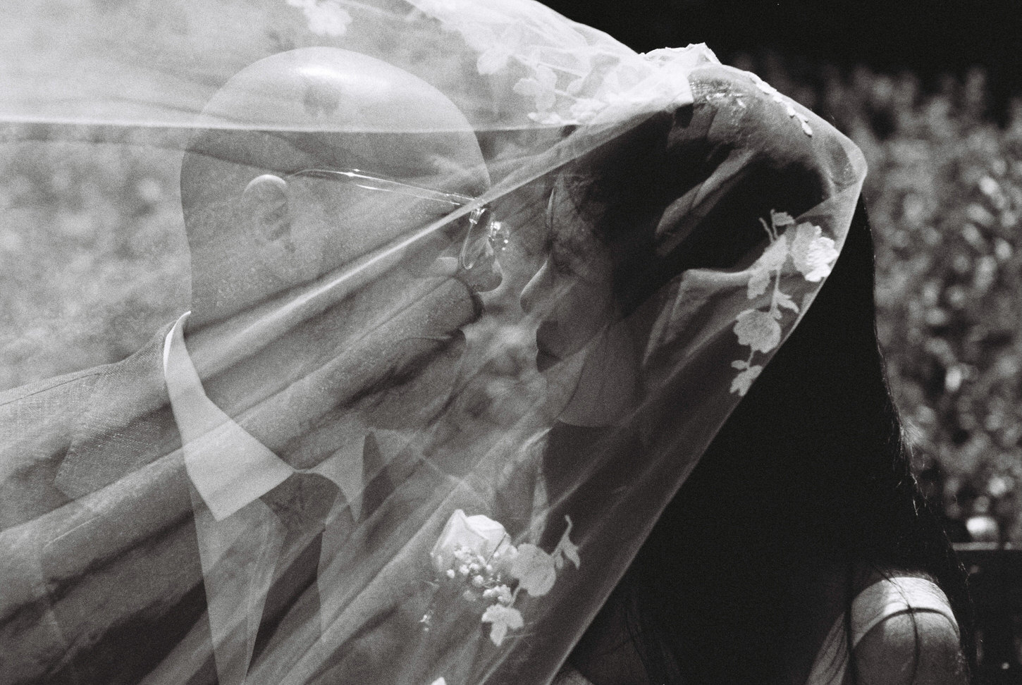 Amazing film photo of the bride and groom about to kiss each other as the veil, moved by the wind, covers their faces, captured by Jenny Fu Studio.