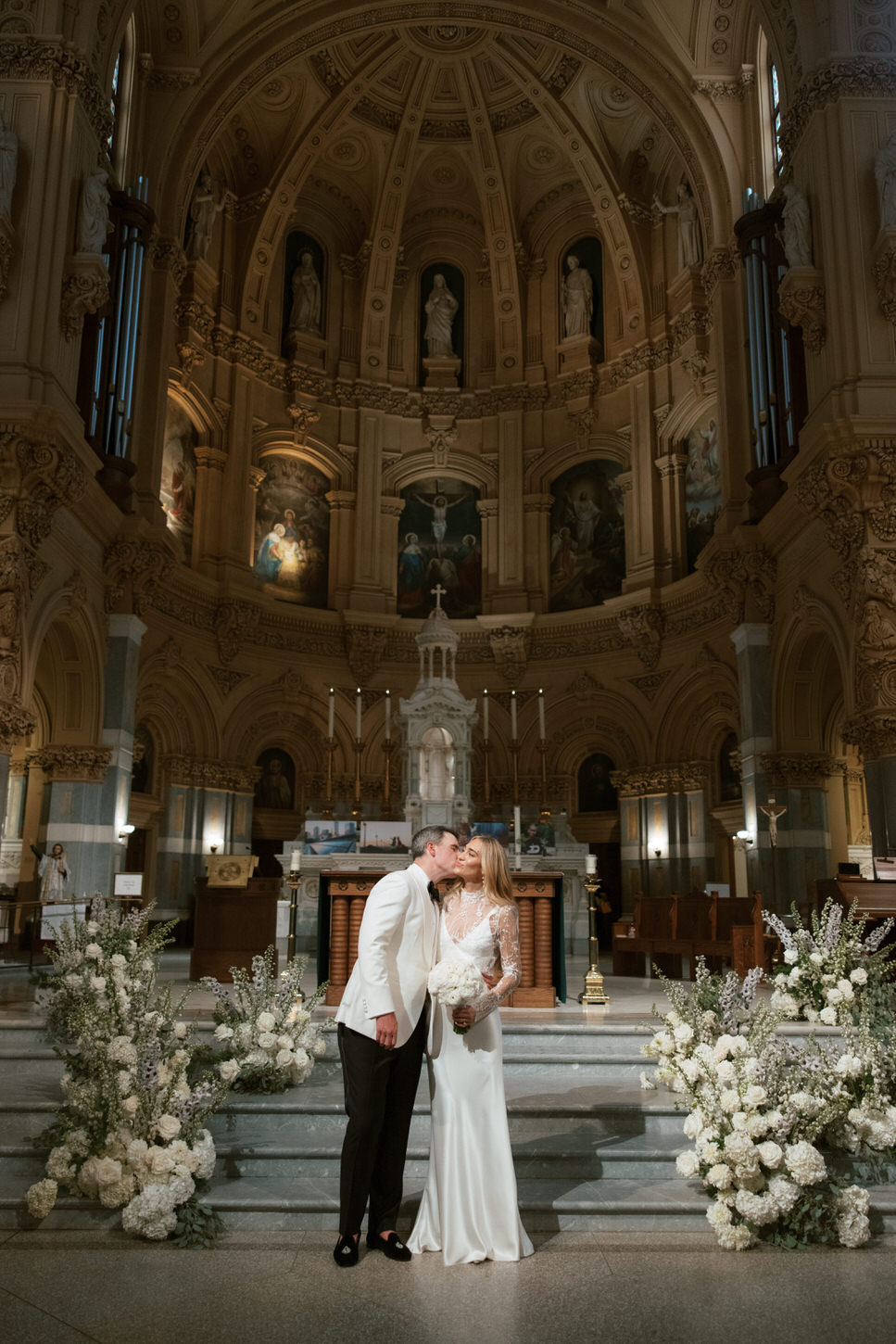 The groom is kissing the bride inside the Cathedral, a NYC wedding photography captured by Jenny Fu Studio.