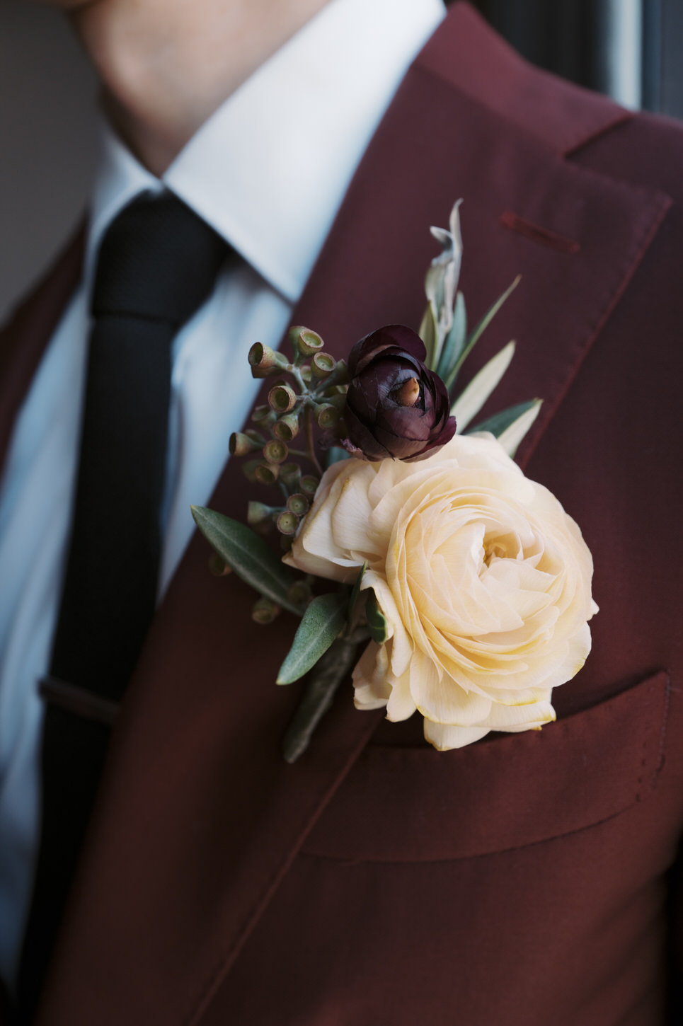 The groom's corsage complements his maroon suit, a cinematic wedding storytelling image by Jenny Fu Studio.