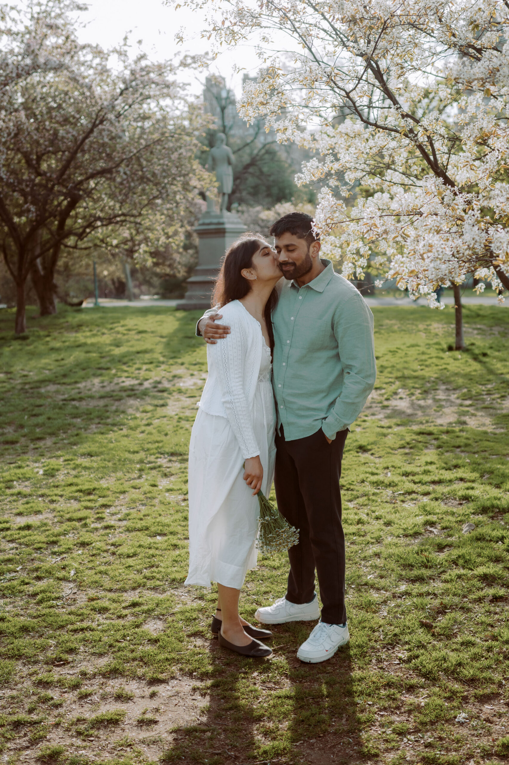 The fiancée is lovingly kissing her fiancé on the nose at Central Park, NYC, captured by Jenny Fu Studio for an authentic wedding storytelling.