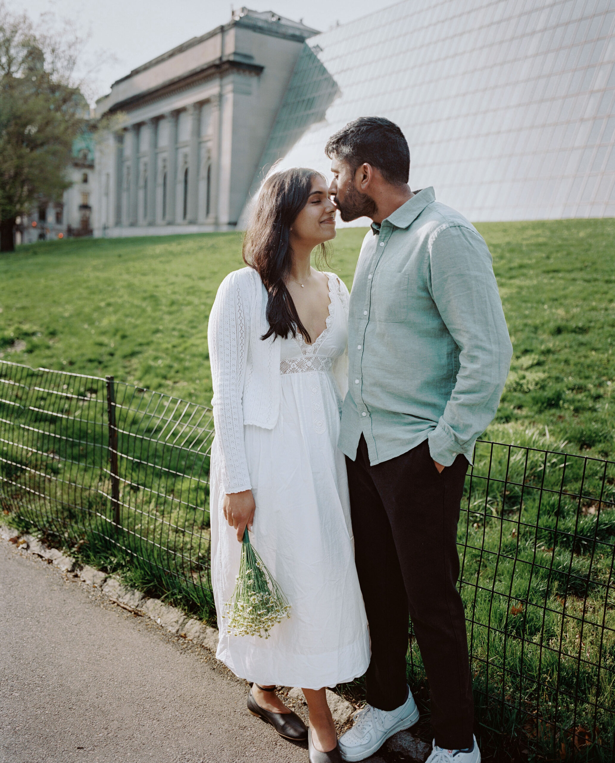 The fiancé is lovingly kissing his fiancée on the nose at Central Park, NYC, captured by Jenny Fu Studio for an authentic wedding storytelling.